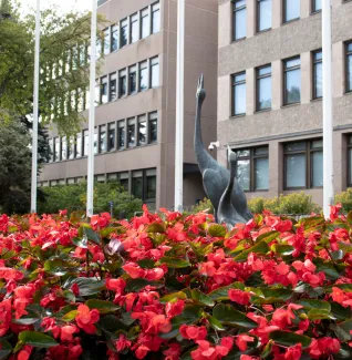 Kaupungintalon pihalla oleva lintupatsas kukkien seassa.