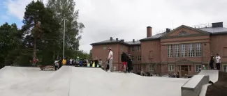 Kuvassa skeittaajia skeittiparkissa, taustalla Tehtaan koulu.