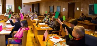 Lastenparlamentti kokoontuu valtuustosalissa, käynnissä on äänestyt vihreillä ja punaisilla lipuilla.