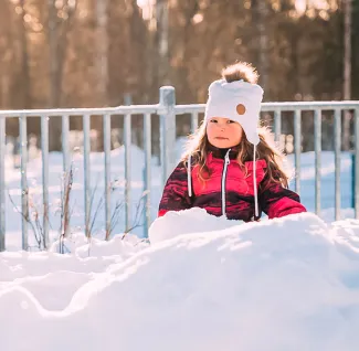 Pieni tyttö lumikinoksessa aurinkoisena talvipäivänä.