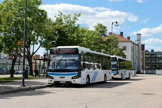 Kaksi paikallisbussia bussipysäkillä peräkkäin.