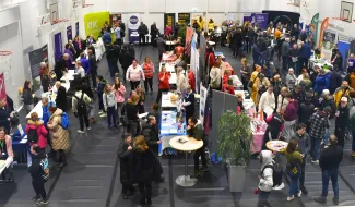 Hurraa Ura! Varkauden kampuksen liikuntasalissa, jossa runsaasti kävijöitä, esittelypöytiä ja eri organisaatioiden ständejä. 